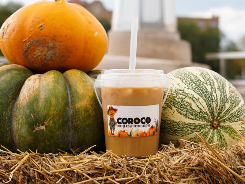 Coroco Coffee Roaster Collective logo with a cheerful scarecrow and a field of pumpkins beneath it.